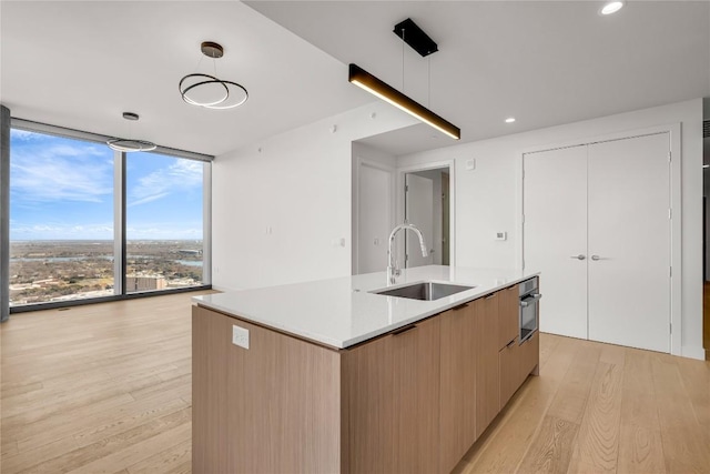 44 E Ave Unit 3107, Austin, TX 78701 - kitchen with a sink, floor to ceiling windows, modern cabinets, a center island with sink, and light wood finished floors