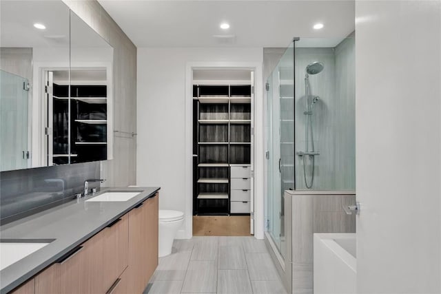 44 E Ave Unit 3107, Austin, TX 78701 - bathroom featuring a shower stall, double vanity, toilet, a spacious closet, and recessed lighting