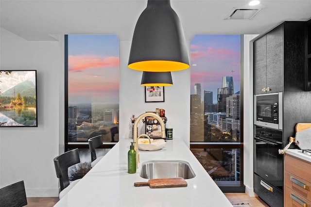 kitchen featuring a sink, built in microwave, a view of city, black oven, and visible vents