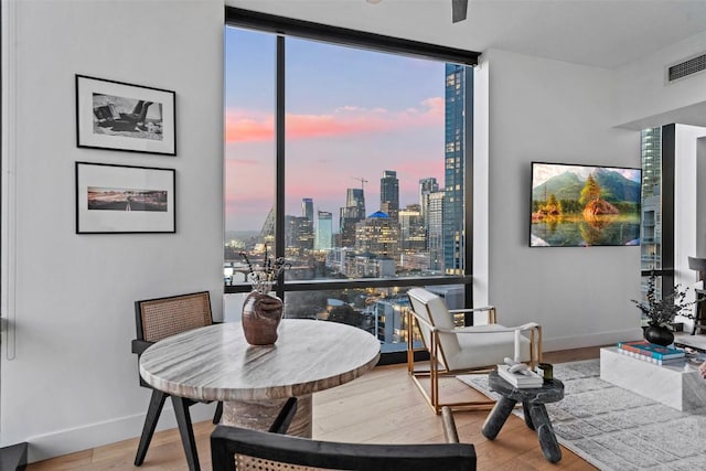 dining space featuring expansive windows, baseboards, wood finished floors, and visible vents