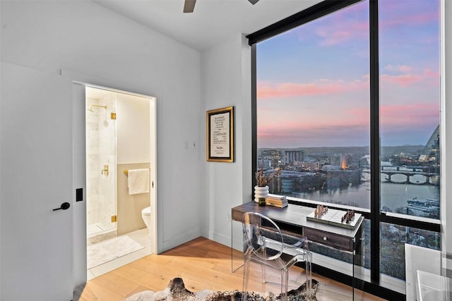 office space featuring wood finished floors, baseboards, ceiling fan, and a view of city