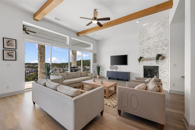 298 Smoke Tree Cir, Dripping Springs, TX 78620 - living room featuring a ceiling fan, beam ceiling, wood finished floors, and a stone fireplace