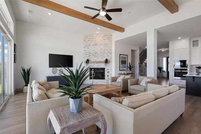 298 Smoke Tree Cir, Dripping Springs, TX 78620 - living room featuring beam ceiling, a ceiling fan, plenty of natural light, light wood-style floors, and a large fireplace