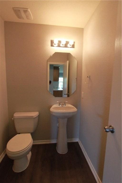 122 Bayliss St, Hutto, TX 78634 - half bathroom featuring visible vents, wood finished floors, baseboards, and toilet