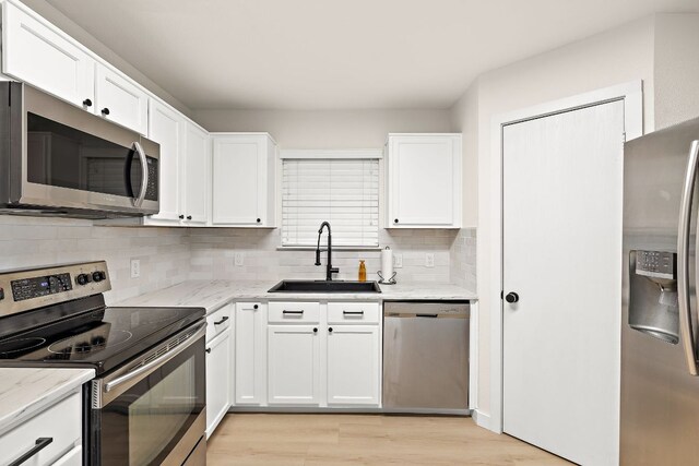 kitchen featuring decorative backsplash, white cabinetry, stainless steel appliances, and a sink