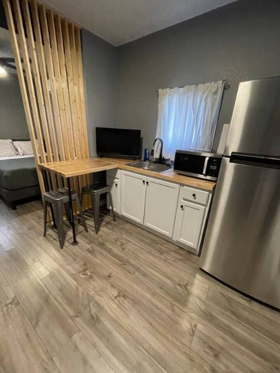 kitchen featuring stainless steel appliances, light wood-style flooring, a sink, and white cabinetry