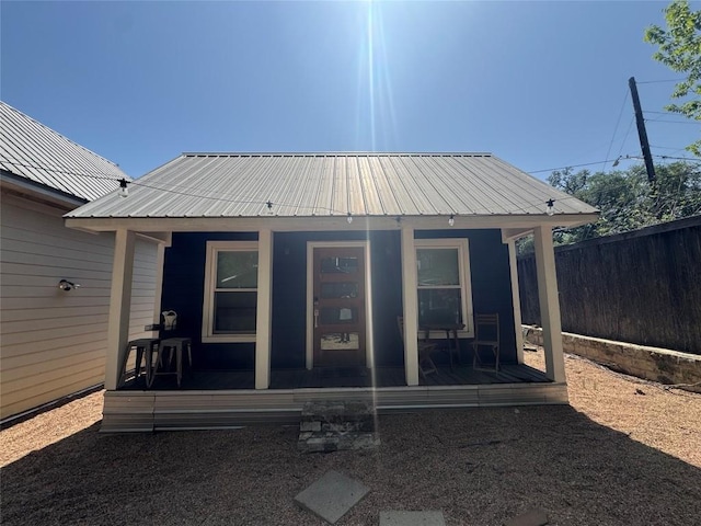rear view of house with a sunroom, metal roof, and fence