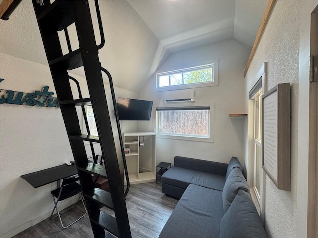 living area with lofted ceiling, wood finished floors, and a wall unit AC