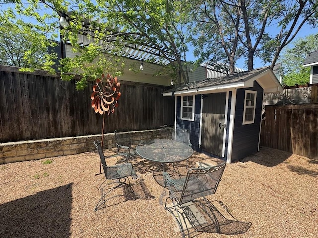 view of patio featuring an outbuilding, a fenced backyard, outdoor dining space, and a storage shed