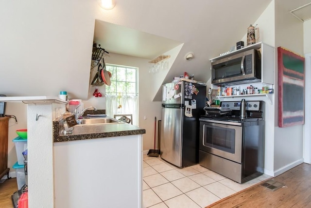 kitchen with a sink, dark countertops, baseboards, visible vents, and appliances with stainless steel finishes