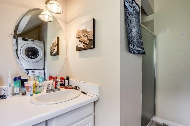 bathroom featuring vanity, stacked washing maching and dryer, and a shower with shower door