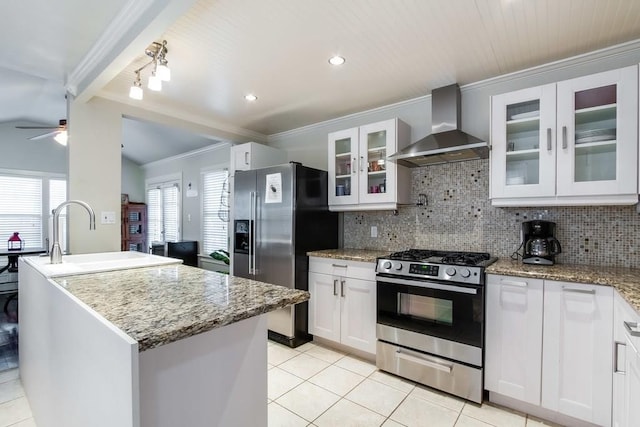 kitchen with ceiling fan, wall chimney exhaust hood, stainless steel appliances, and light tile patterned floors