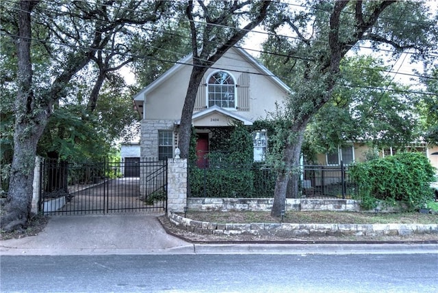 view of front of home featuring stucco siding, stone siding, a fenced front yard, and a gate