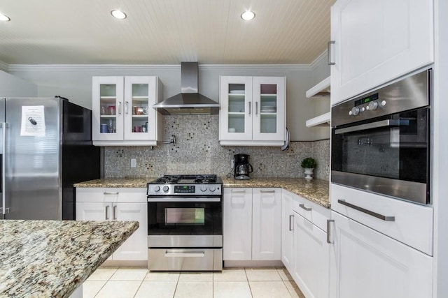 kitchen with wall chimney exhaust hood, white cabinets, light tile patterned flooring, crown molding, and appliances with stainless steel finishes