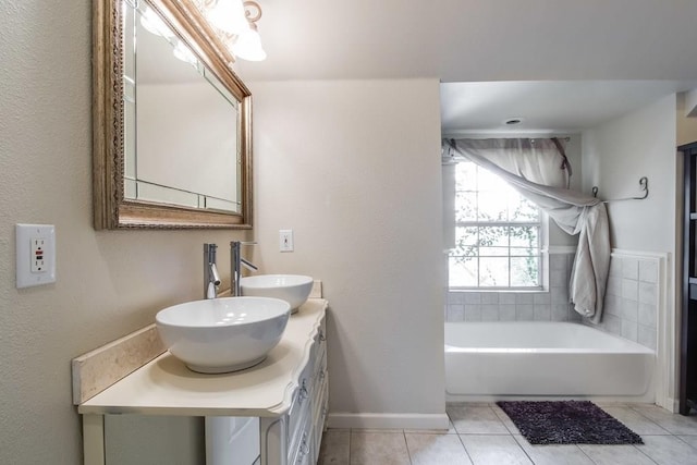full bathroom featuring a bath, tile patterned floors, baseboards, and a sink