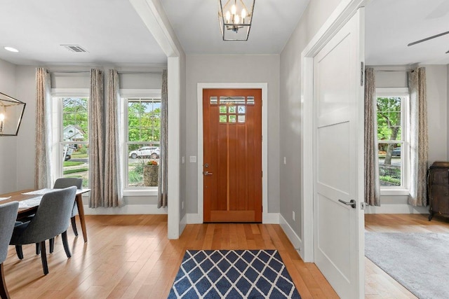 foyer with baseboards, a chandelier, visible vents, and light wood-style flooring
