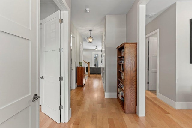 hall featuring light wood-style floors, stairway, and baseboards