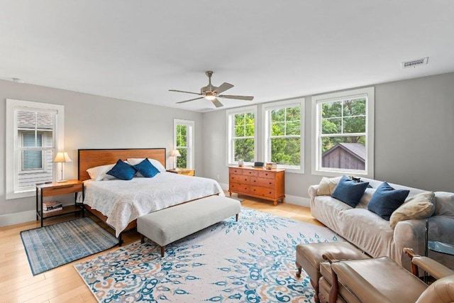 bedroom with light wood-style floors, visible vents, a ceiling fan, and baseboards
