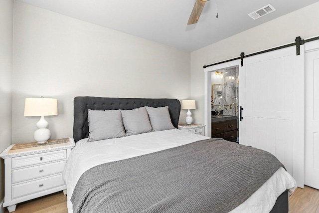 7993 W Fm 487, Florence, TX 76527 - bedroom with a barn door, wood finished floors, and ceiling fan