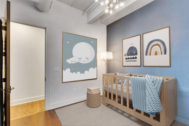 800 W 5th St Unit 1008, Austin, TX 78703 - bedroom featuring wood finished floors, a crib, a chandelier, beamed ceiling, and baseboards