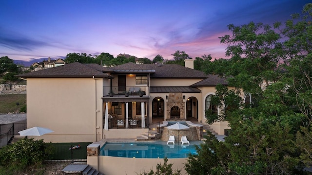 3708 Lajitas, Leander, TX 78641 - back of house at dusk with a balcony, a patio area, stucco siding, a chimney, and a hot tub