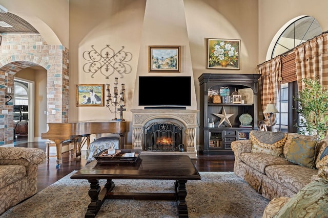 3708 Lajitas, Leander, TX 78641 - living area with a lit fireplace, arched walkways, a high ceiling, and wood finished floors