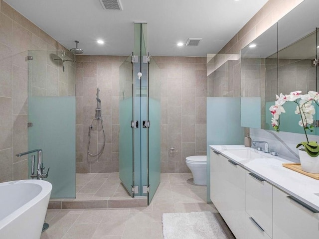 44 E Ave Unit 4305, Austin, TX 78701 - full bathroom with tile walls, a stall shower, double vanity, a freestanding bath, and tile patterned flooring