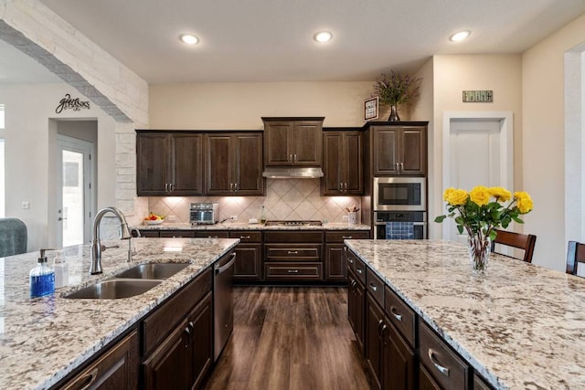 629 Asher Ct, Leander, TX 78641 - kitchen featuring appliances with stainless steel finishes, dark wood-style flooring, tasteful backsplash, light stone counters, and dark brown cabinets