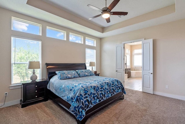 629 Asher Ct, Leander, TX 78641 - carpeted bedroom featuring multiple windows, a raised ceiling, ensuite bathroom, and a ceiling fan