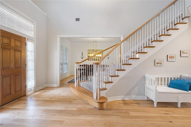 foyer featuring wood finished floors, stairway, baseboards, and a towering ceiling