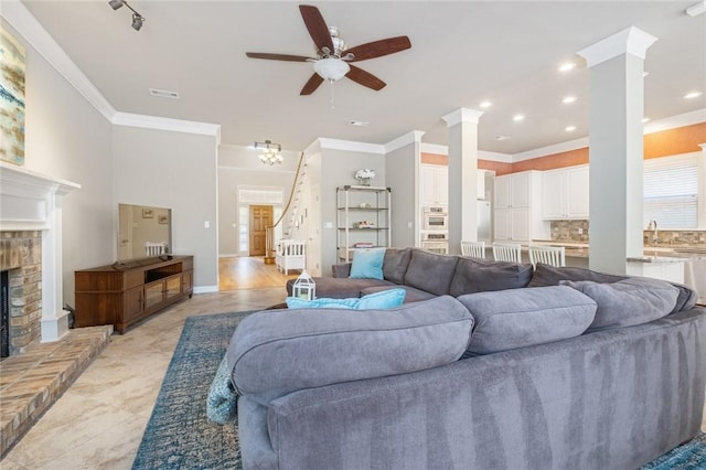 living room featuring ornamental molding, ceiling fan, ornate columns, stairway, and a fireplace