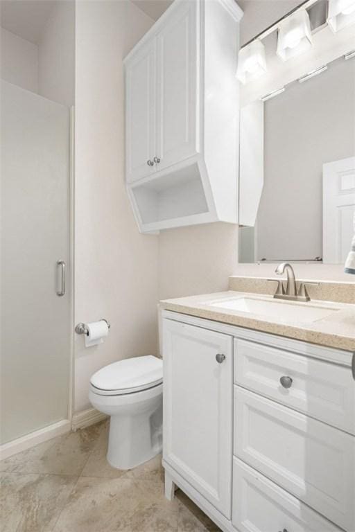 bathroom with toilet, vanity, an enclosed shower, and baseboards