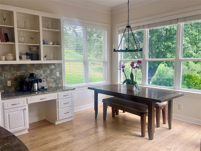 dining room with light wood-type flooring, baseboards, and crown molding