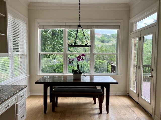 dining room featuring baseboards, light wood-style flooring, and ornamental molding