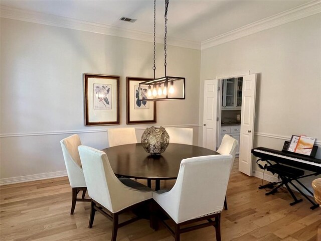 dining area with ornamental molding, light wood-type flooring, and baseboards