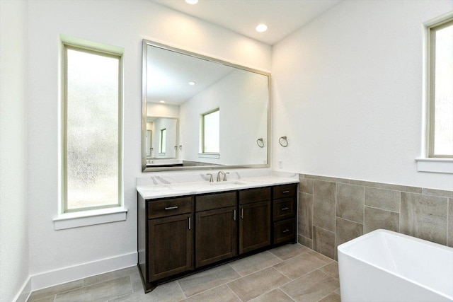 full bathroom with vanity, a soaking tub, tile patterned floors, and tile walls