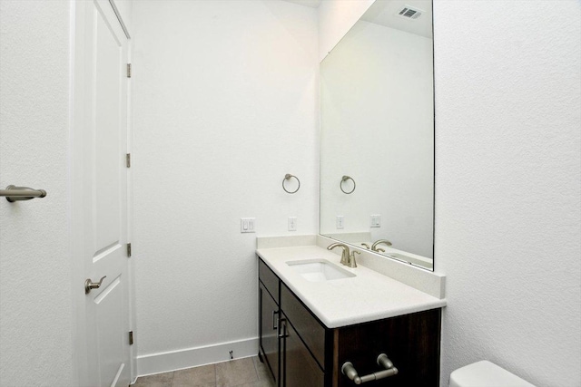 half bathroom featuring baseboards, visible vents, vanity, and toilet
