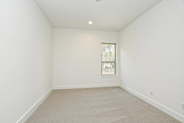 spare room with baseboards, recessed lighting, and light colored carpet