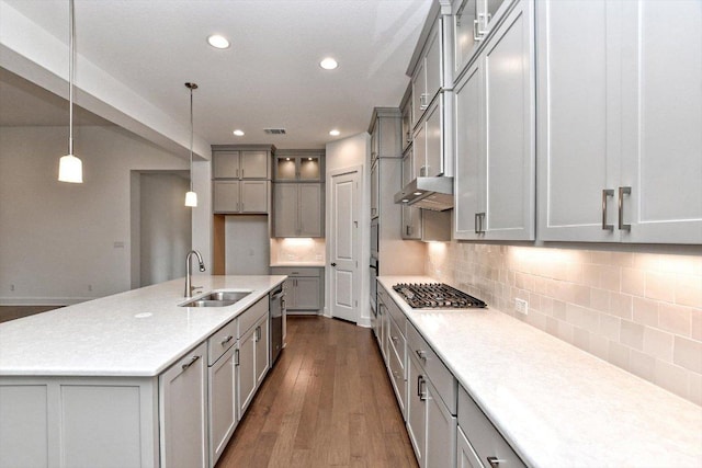 kitchen with a sink, visible vents, gray cabinets, under cabinet range hood, and dark wood-type flooring