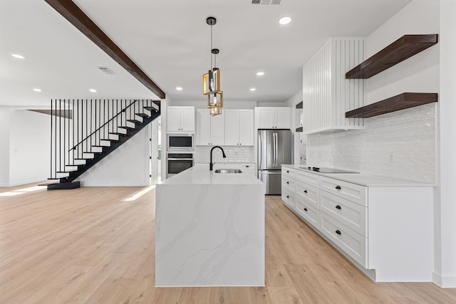 208 Ulupau Cir, Bastrop, TX 78602 - kitchen featuring open shelves, stainless steel appliances, light wood finished floors, white cabinetry, and tasteful backsplash