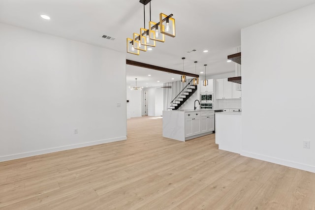 208 Ulupau Cir, Bastrop, TX 78602 - unfurnished living room featuring a chandelier, light wood-style floors, recessed lighting, and stairway