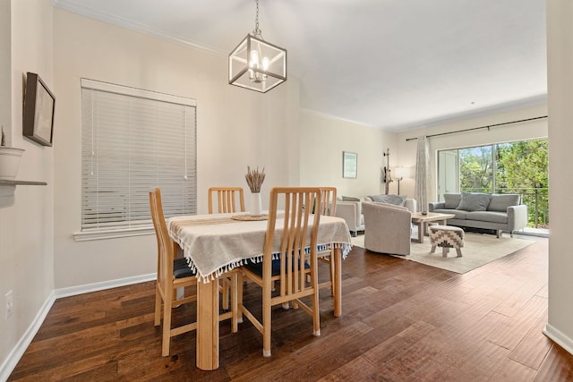 dining space featuring dark wood-style flooring, a notable chandelier, crown molding, and baseboards