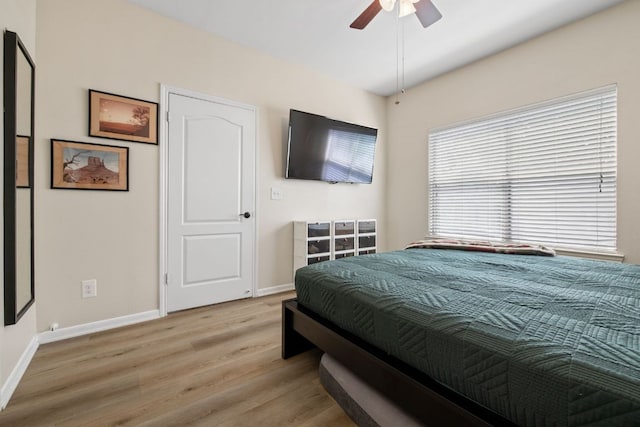 bedroom featuring baseboards, a ceiling fan, and light wood finished floors