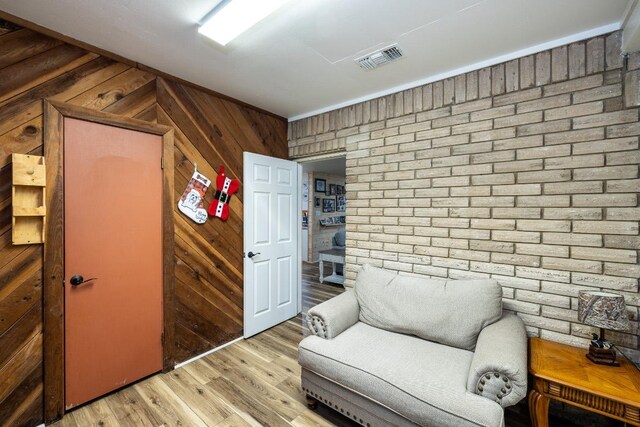 110 Live Oak St, Gonzales, TX 78629 - sitting room featuring brick wall, wooden walls, light wood-style floors, and visible vents