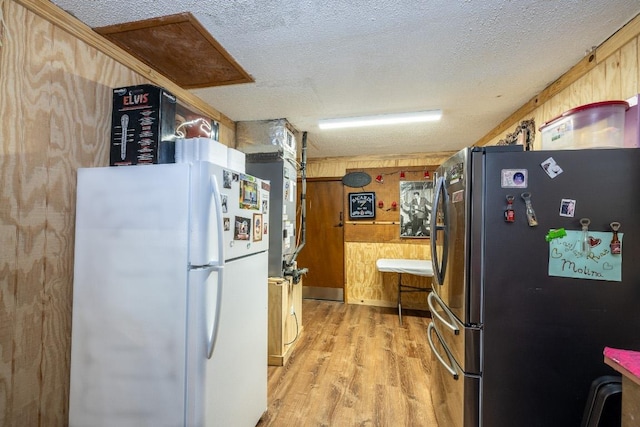 110 Live Oak St, Gonzales, TX 78629 - kitchen featuring wood walls, light wood-style flooring, freestanding refrigerator, and a textured ceiling