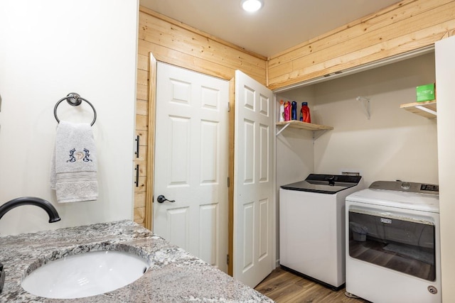 110 Live Oak St, Gonzales, TX 78629 - laundry room with wood walls, laundry area, wood finished floors, a sink, and washing machine and clothes dryer
