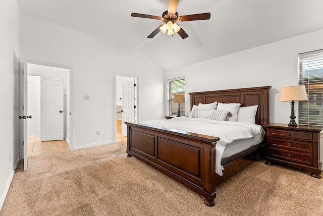 bedroom with ceiling fan, vaulted ceiling, baseboards, light colored carpet, and ensuite bathroom