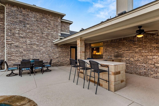 view of patio featuring outdoor dining area, outdoor dry bar, ceiling fan, and a sink