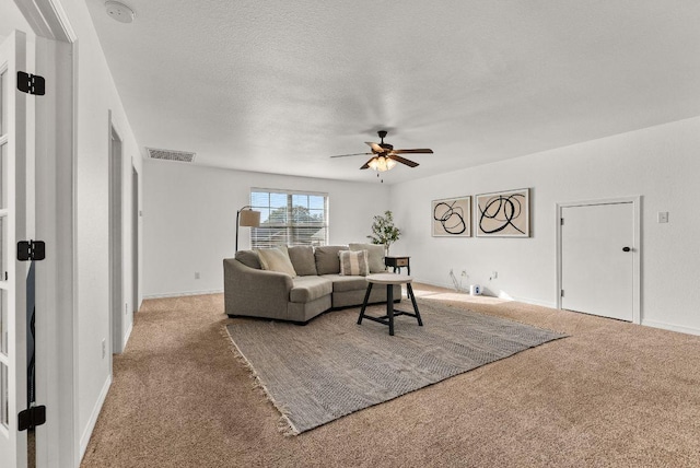 living room featuring visible vents, carpet flooring, baseboards, and a ceiling fan