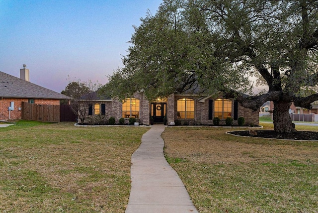 view of front of property featuring brick siding, a front lawn, and fence